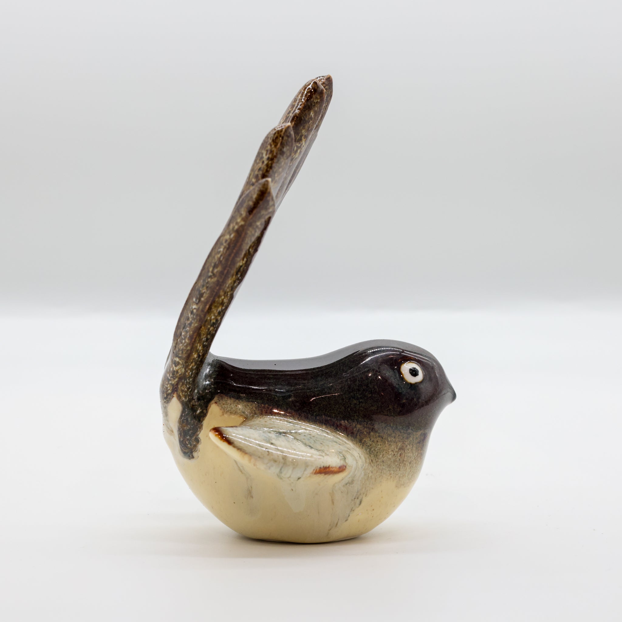 Pīwakawaka ceramic sculpture displayed on a wooden surface