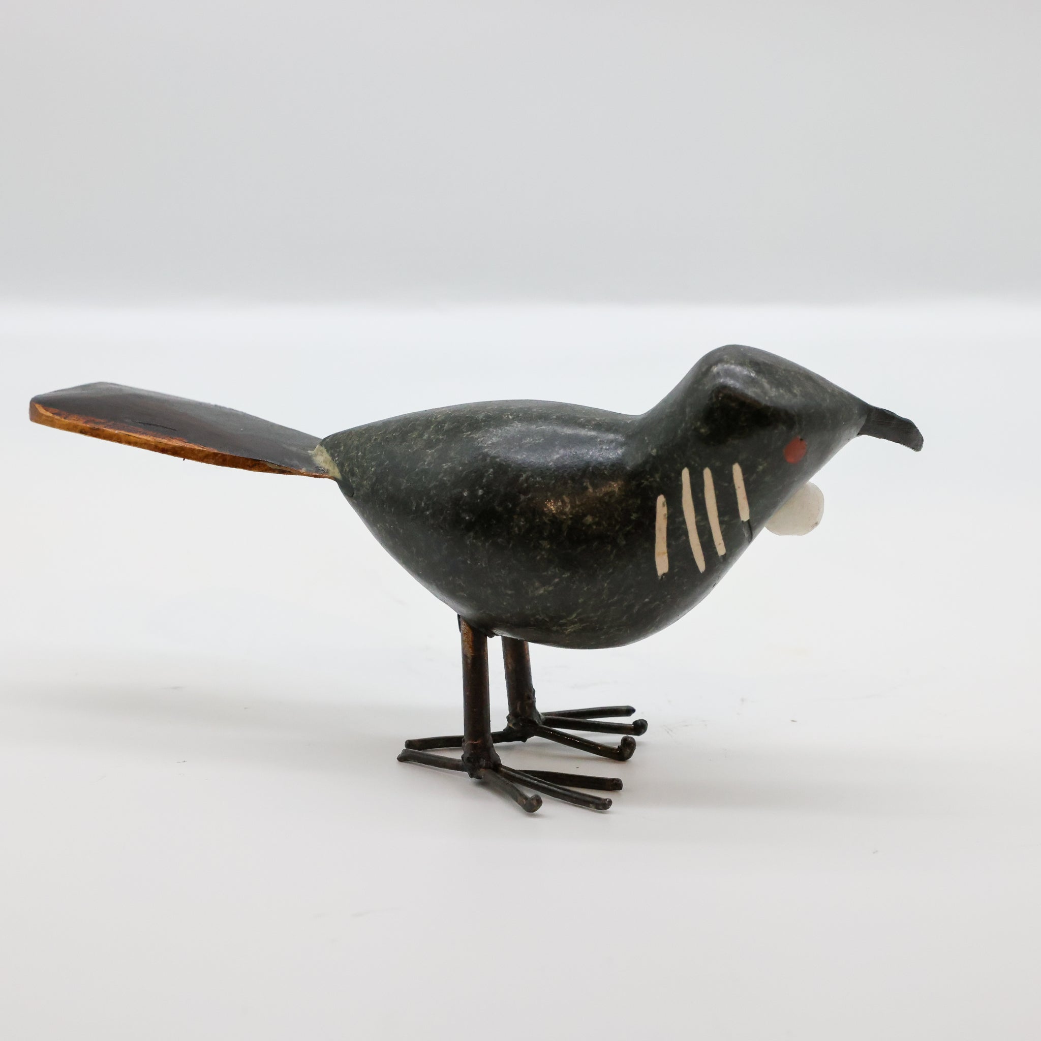 Stone Tūī sculpture displayed on a wooden surface
