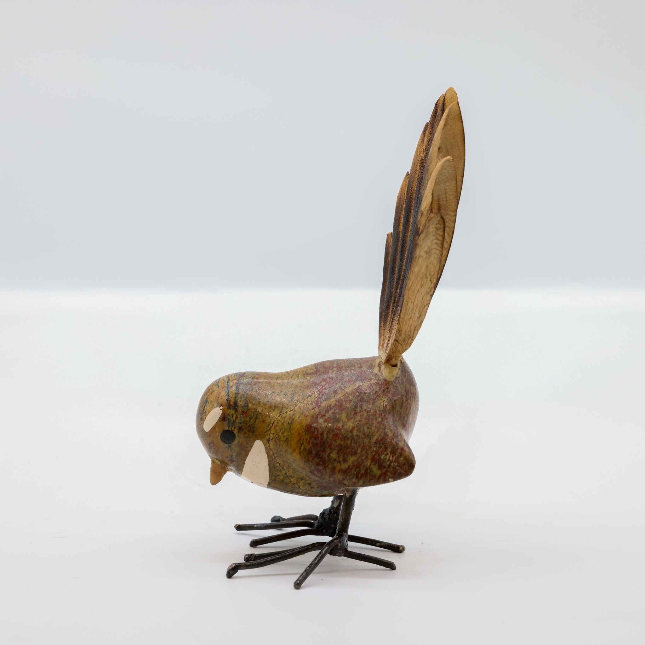 Stone Pīwakawaka sculpture displayed on a wooden surface