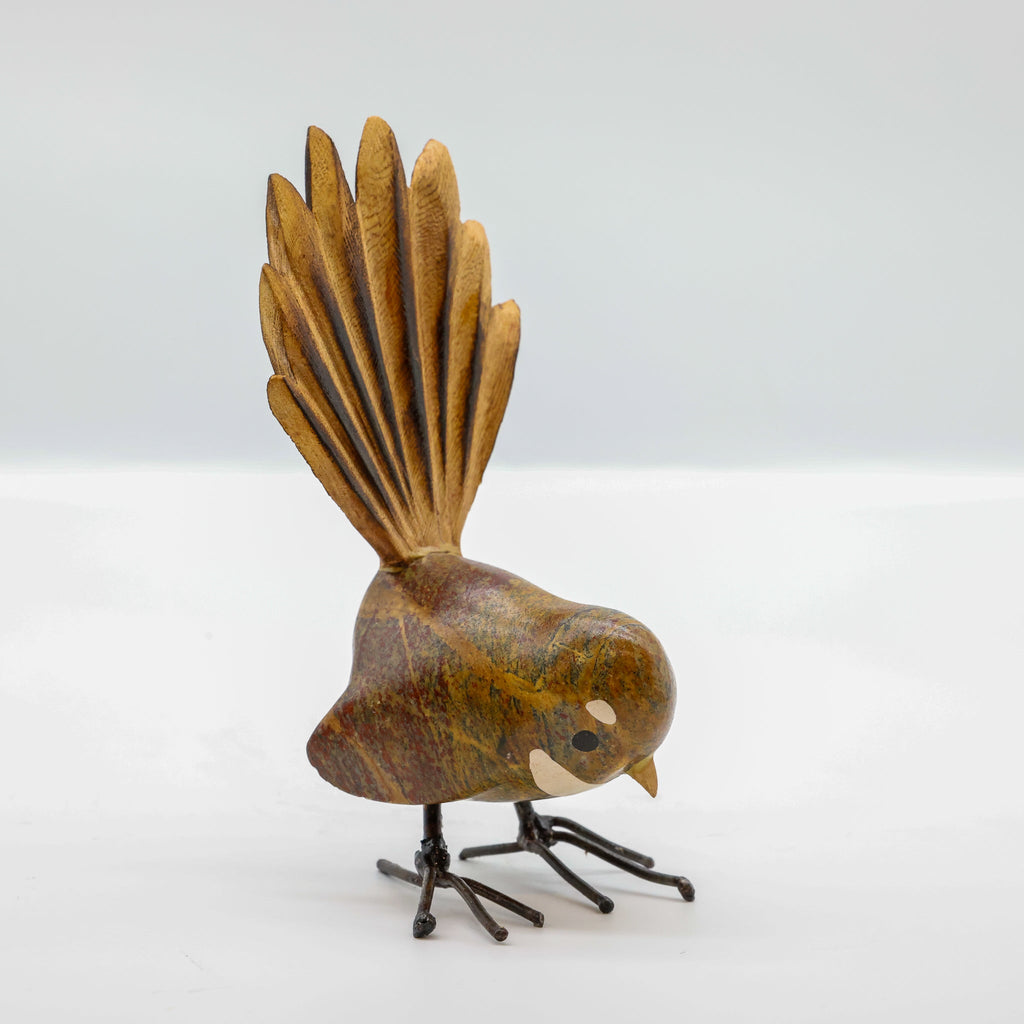Stone Pīwakawaka sculpture showing carved wooden fanned tail