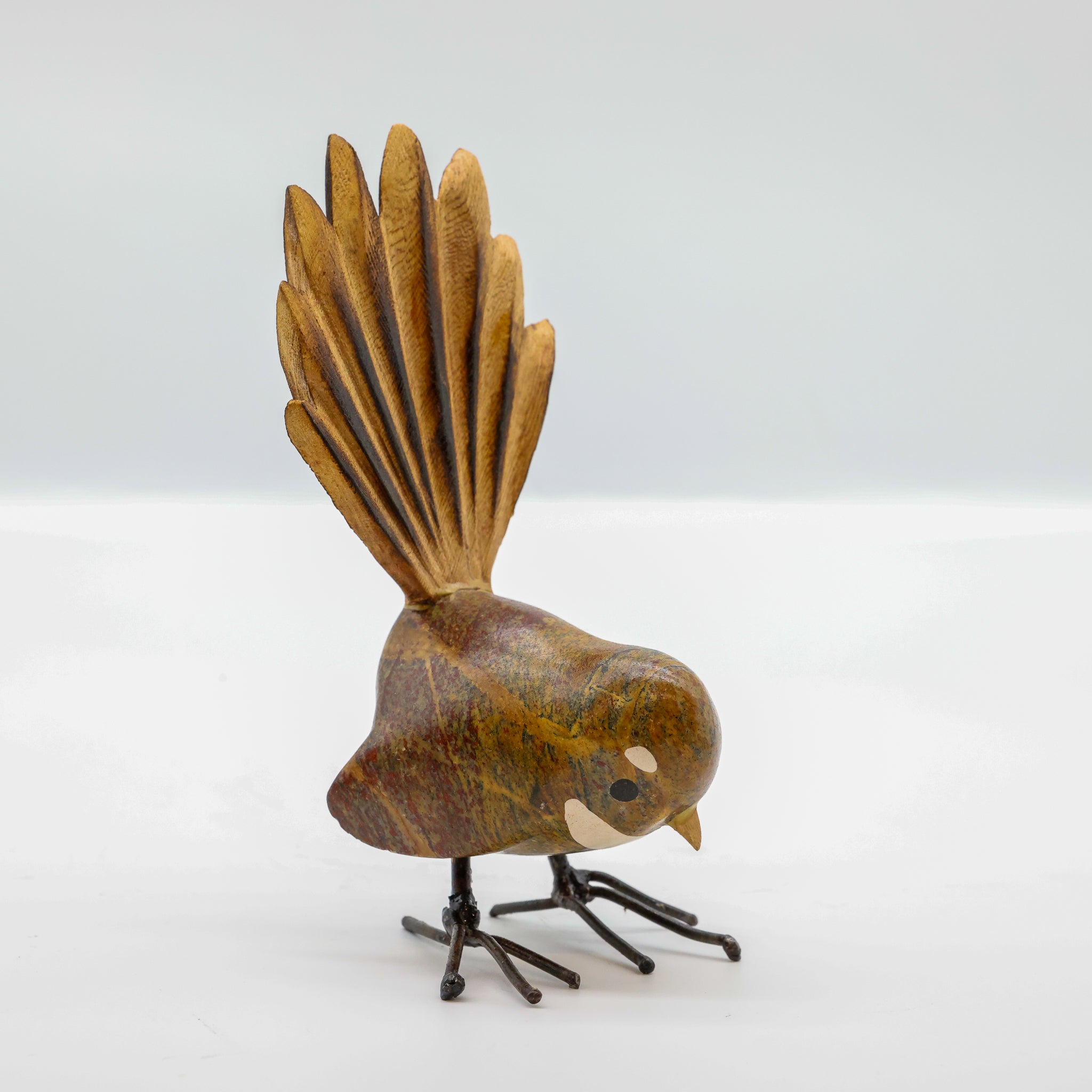 Stone Pīwakawaka sculpture showing carved wooden fanned tail